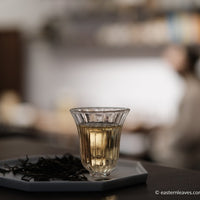 Pu'er shengpu Chinese tea pressed cake brick vintage and aged, 2017 spring harvest, tea forest, yellow brew liquor in glass cup, golden buds, from Nannuo in Yunnan